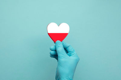 Midsection of man holding heart shape against blue background