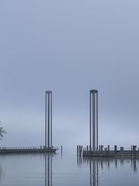 Wooden posts in lake against clear sky