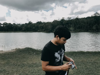 Boy standing by lake against plants
