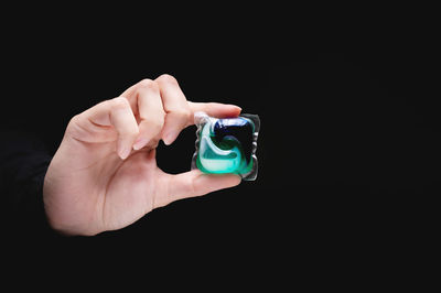 Close-up of hand holding electronic cigarette against black background