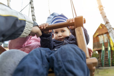 Portrait of siblings sitting on slide at playground