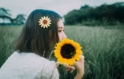 Close-up of woman with yellow flower on field