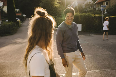 Mature man looking at woman while standing on road during sunny day