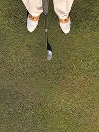 Low section of man with golf club standing on grass
