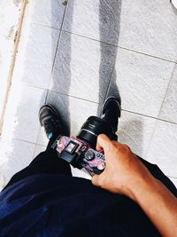 Low section of man holding camera on tiled floor