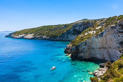 Scenic view of sea and rocks against clear blue sky