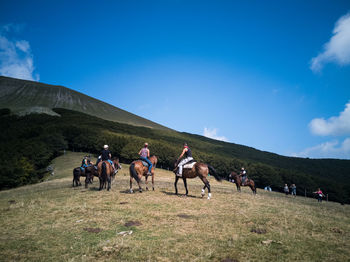 People riding horses on land against sky