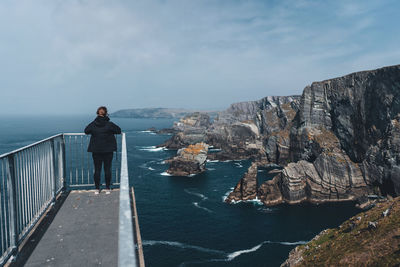 Rear view of man looking at sea against sky