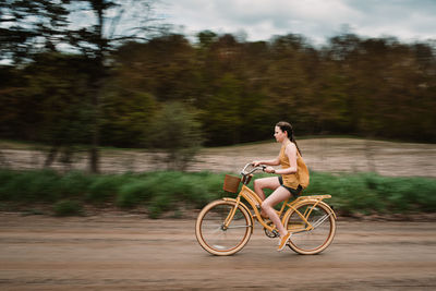 Rear view of man riding bicycle on field