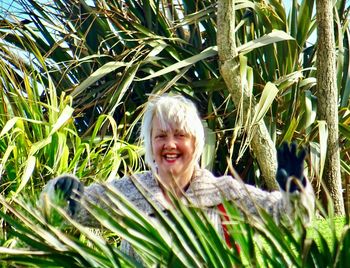 Portrait of smiling mature woman standing amidst plants