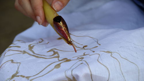 Cropped hand of person making batik over fabric