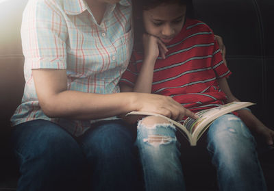 Rear view of friends sitting on book