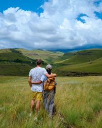 Rear view of people walking on field against sky