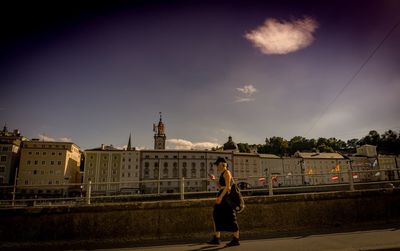 Rear view of woman standing against cloudy sky