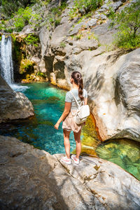 Rear view of man standing against waterfall