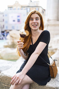 Funny woman with ice cream cone sitting in city