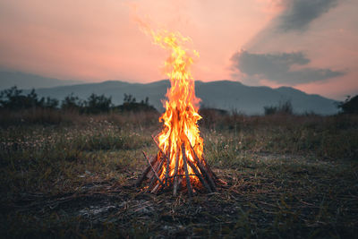 Bonfire on field against sky during sunset