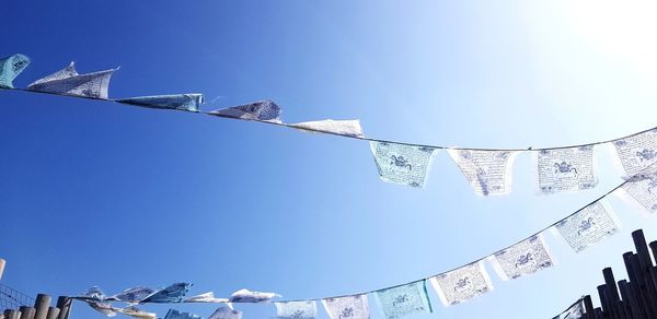 Low angle view of clothes hanging against blue sky