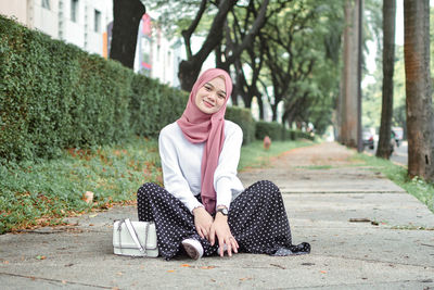 Portrait of young woman sitting on road