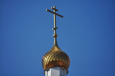 Low angle view of cross against building against clear blue sky