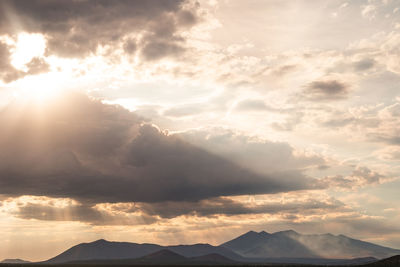 Low angle view of sunlight streaming through clouds