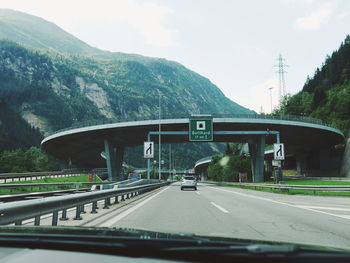 Cars on road by bridge against sky