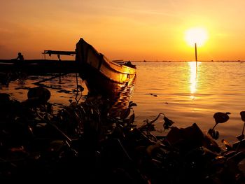 Boat in calm sea at sunset