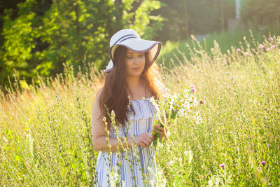 Woman wearing hat standing on field