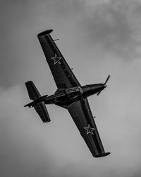 Historic airplane flying in front of the clouds during an airshow.