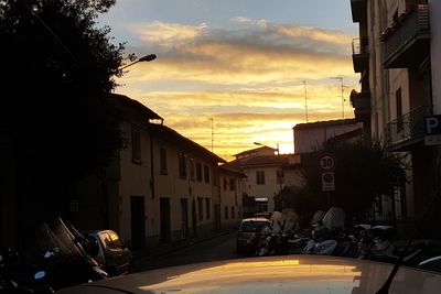 Cars on street against sky during sunset