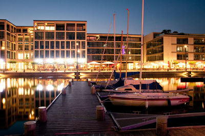 Boats moored in illuminated city against clear sky at night