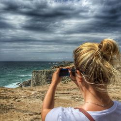 Rear view of woman photographing at seaside