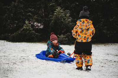 Full length of boys on snow covered tree