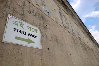 Low angle view of road sign against wall