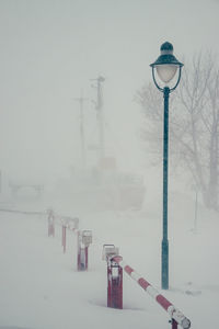 Street light covered with snow against sky