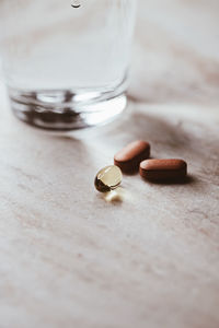 Close-up of pills with glass of water on table