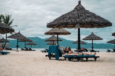 Lounge chairs and parasols on beach against sky