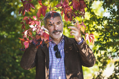 A mature man posing against the backdrop of thickets of wild grapes.