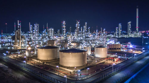 High angle view of illuminated factory in city at night