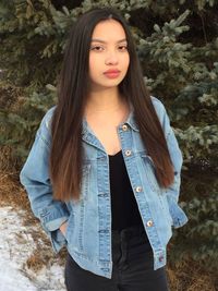 Portrait of young woman standing against tree