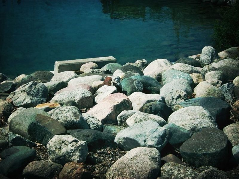 rock - object, stone - object, water, pebble, nature, abundance, tranquility, stone, rock, stack, large group of objects, beauty in nature, outdoors, tranquil scene, day, high angle view, scenics, log, lake