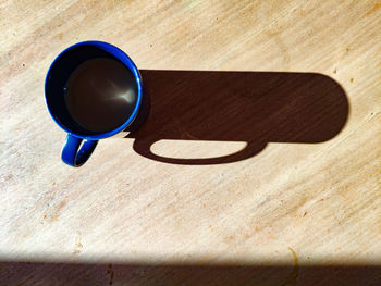 High angle view of coffee cup on table with a long shadow 