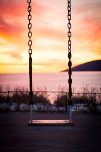 Close-up of swing at playground against sky during sunset