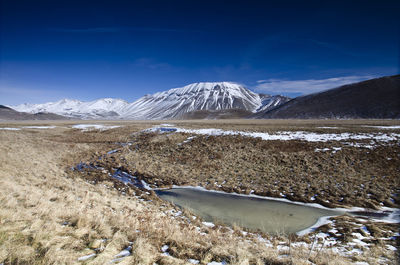 Scenic view of snowcapped mountains against blue sky