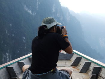 Rear view of woman photographing while sitting on boat