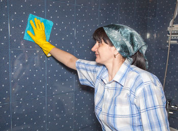 Woman wiping tiled wall