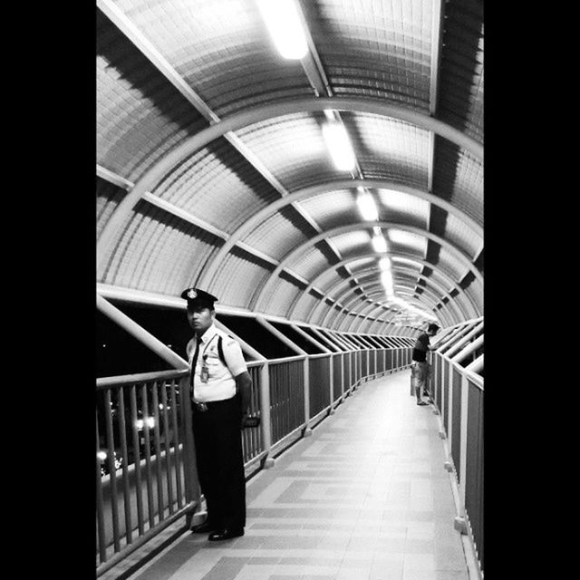 indoors, full length, lifestyles, the way forward, rear view, walking, tunnel, leisure activity, diminishing perspective, ceiling, casual clothing, standing, architecture, built structure, subway, illuminated, men, person