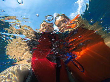 Low angle view of couple wearing life jackets seen from underwater