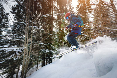 A male athlete skier rides a freeride in a winter forest in the mountains. jump against the backdrop