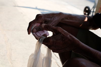 Close-up of man holding paper currency and plastic bag outdoors